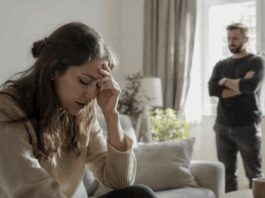 Млада жена под стрес и маж во позадина како знаци за емоционална манипулација